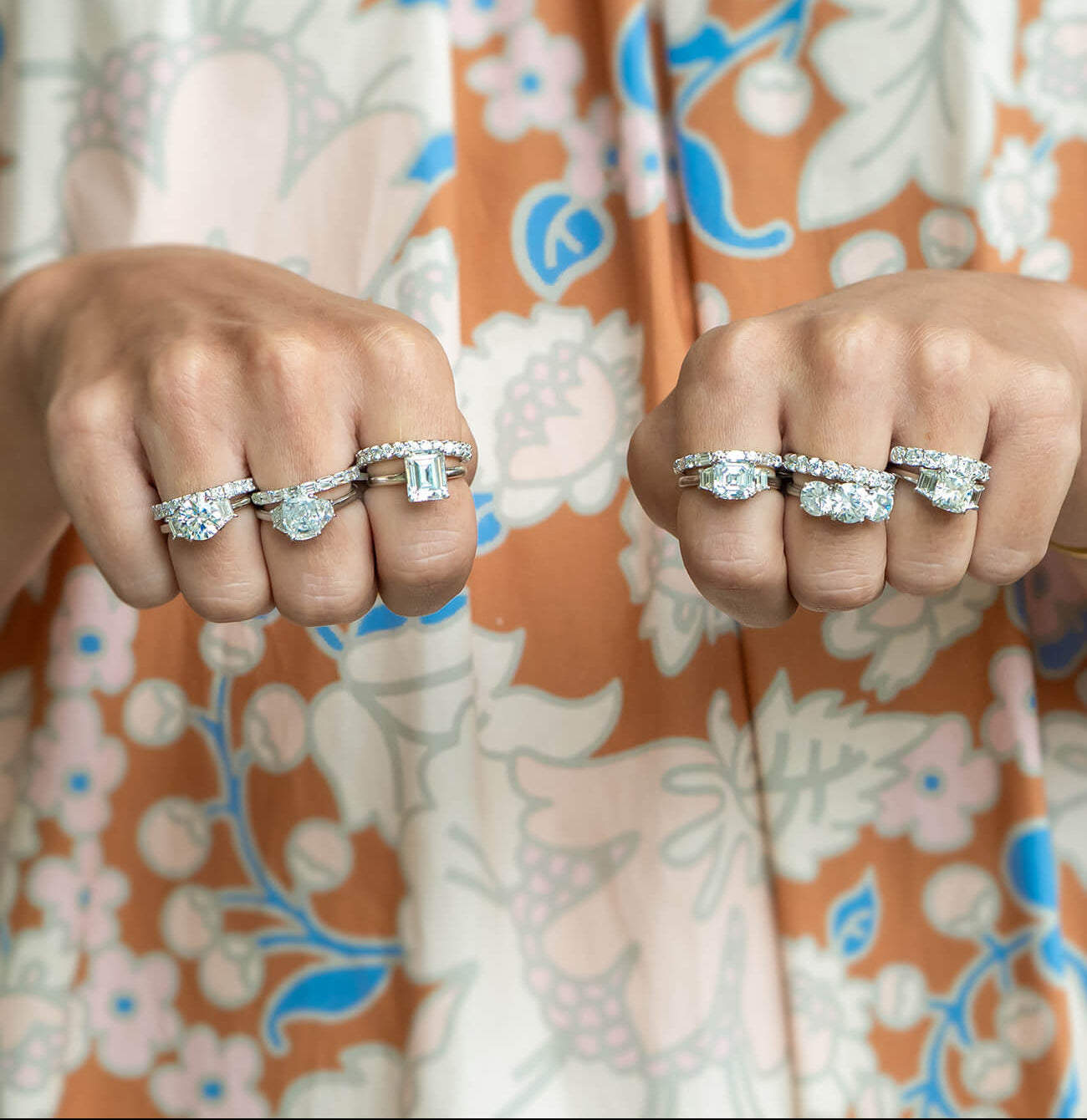 Woman wearing multiple custom designed diamond engagement rings created by Laura Pearce against a floral background