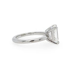 A platinum ring featuring an emerald-cut clear diamond in a prong setting, shown from a side angle against a plain white background.