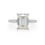 An emerald-cut diamond solitaire ring in a polished platinum metal band, set against a plain white background.