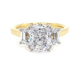 18K yellow gold ring with cushion cut center diamond and smaller trapezoid diamonds on the sides against a white background