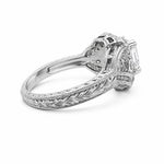 An ornate platinum diamond ring with a filigree band and an Asscher-cut center stone, shown from a side angle on a white background.