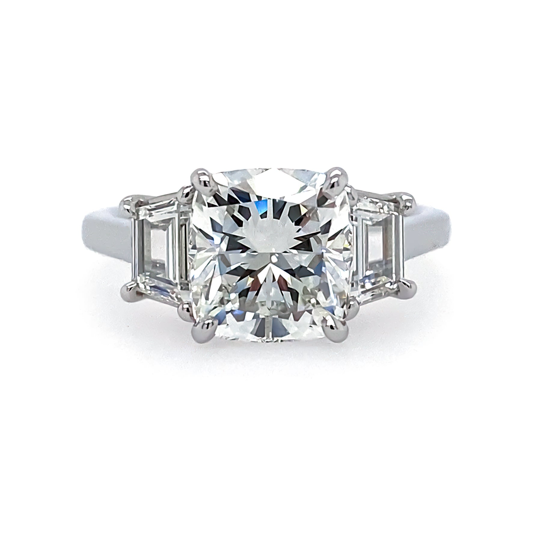 A platinum cushion cut diamond ring with side trapezoid diamonds