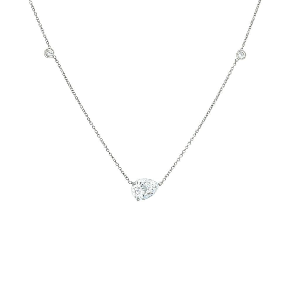 A platinum necklace with a solitaire diamond pendant surrounded by smaller clear crystals.