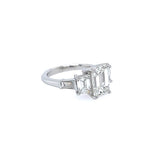 A custom platinum five-stone diamond ring featuring an emerald-cut center stone and baguette-cut side stones, set on a plain white background.