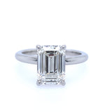 A platinum emerald cut solitaire ring with a clear, center stone, showcasing the ring's design and setting.