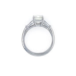 A platinumsolitaire engagement ring featuring an emerald cut center stone in a four-prong setting, with two baguette side stones, shown on a plain white background.