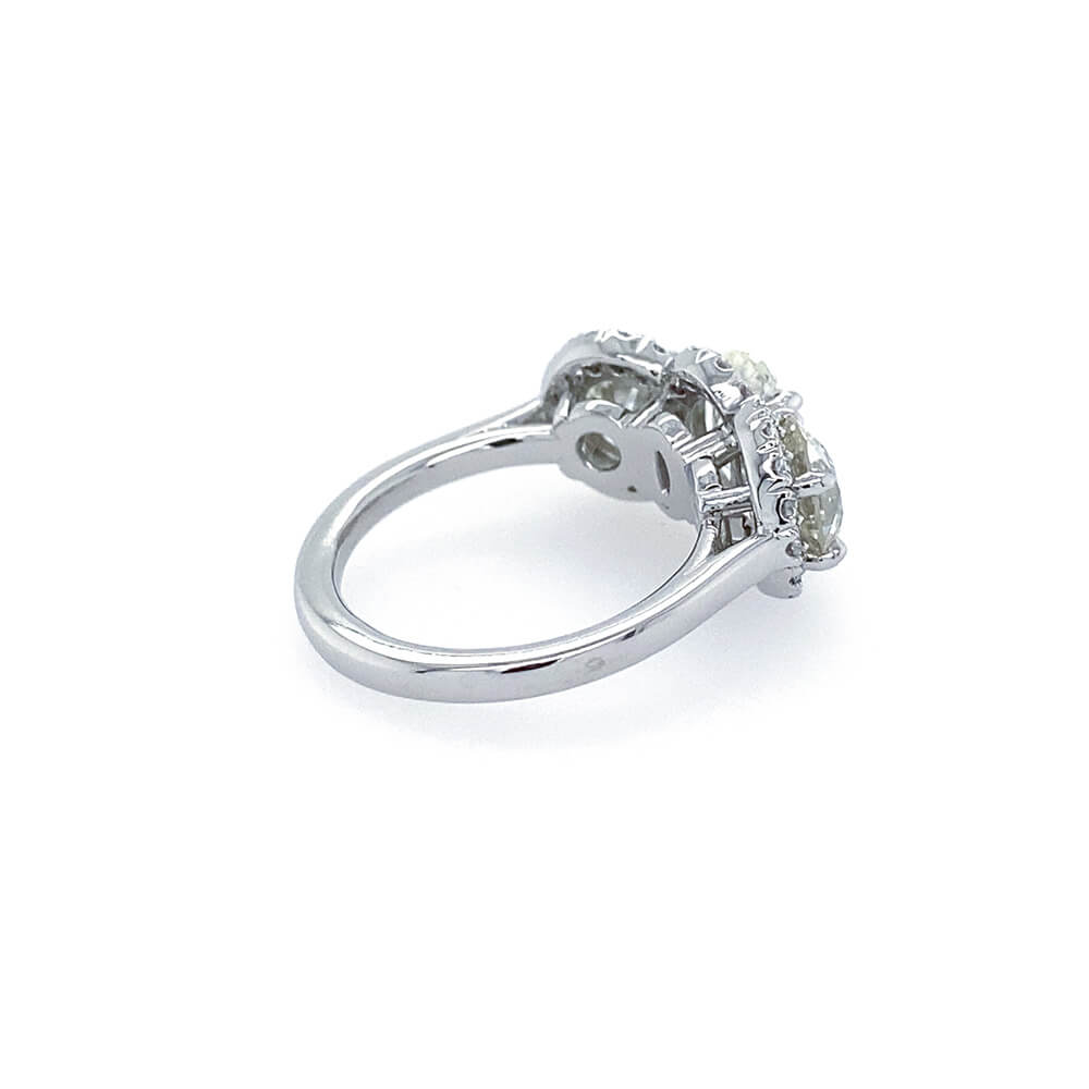 A platinum ring with a three diamonds with diamond halos