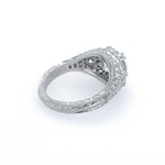 A platinum diamond ring with a textured, filigree band and a cluster of small diamonds on the top, photographed on a clean white background.