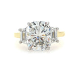 A three-stone diamond ring featuring a large elongated cushion cut center diamond flanked by two trapezoid side diamonds on an 18K yellow gold band, set against a plain white background.
