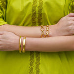 Close-up of a woman wearing Elizabeth Locke 19K gold jewelry on a green background