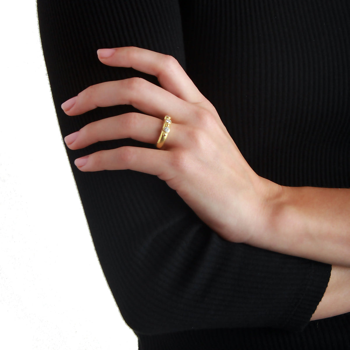 Hand wearing a 19K gold and diamond ring with a black sweater background