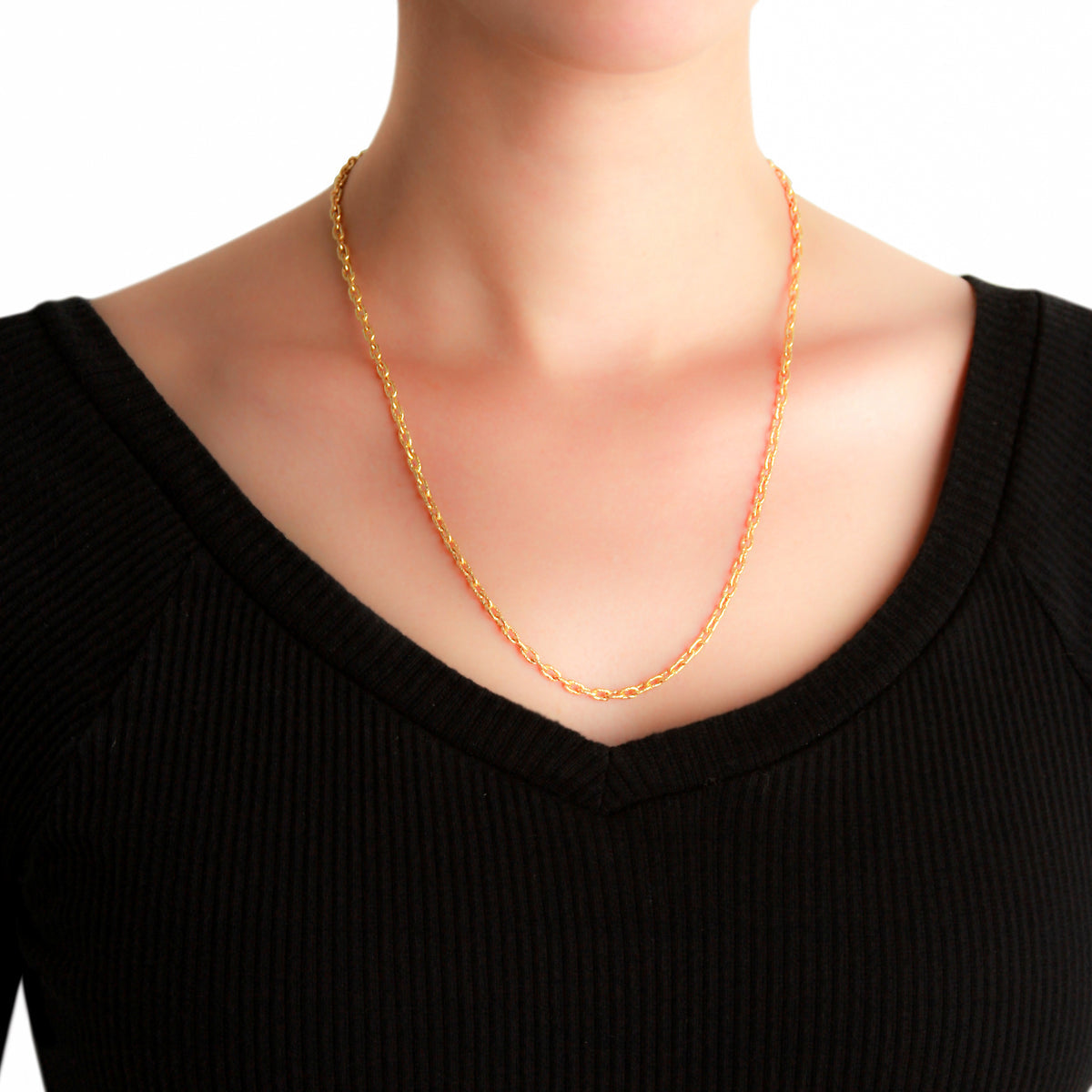 19K Gold chain necklace on a woman wearing a black top against a white background