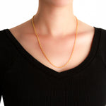 19K Gold chain necklace on a woman wearing a black top against a white background