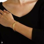 19K Gold bracelet on a woman's wrist with a black background 