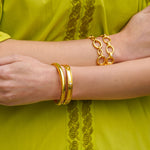 Close-up of woman wearing Elizabeth Locke gold jewelry on a green outfit background