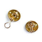 A back view of a pair of gold-toned oval earrings shown from the back on a clean white background, displaying the metal backing and spring clasp mechanism.