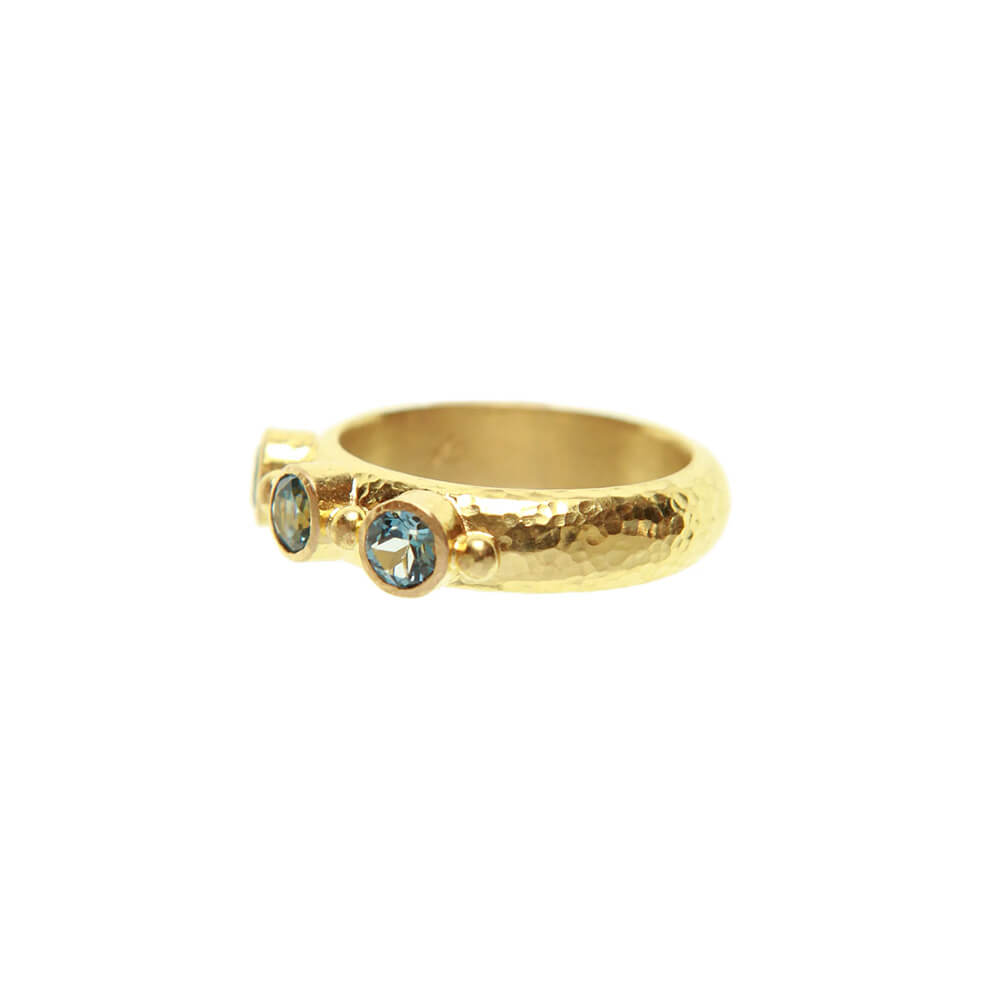 An Elizabeth Locke 19K yellow gold ring with a hammered texture and three bezel-set round green aquamarine gemstones, shown on a plain white background.