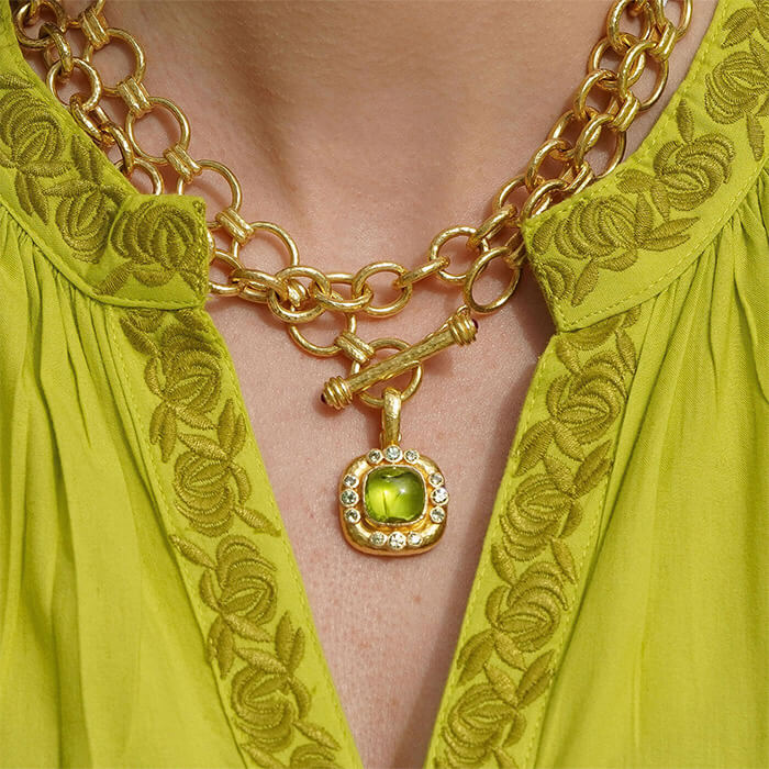 18K Gold chain necklace with a green Peridot gemstone pendant on a woman wearing a green top.