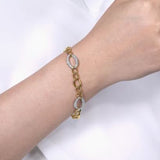 Yellow and White Gold bracelet with diamond accents on a wrist against a white background