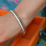 Woman wearing 18K yellow gold sapphire bracelet and diamond bracelet