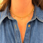 Close-up of a woman wearing a 18K gold necklace with floral pendants,