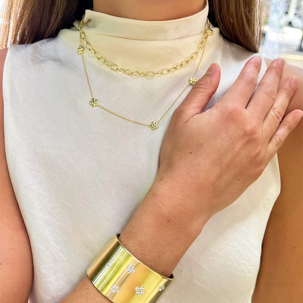 Close-up of a woman wearing 18K gold jewelry including a necklace and bracelet designed by Laura Pearce