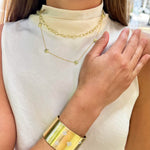 Close-up of a woman wearing 18K gold jewelry including a necklace and bracelet designed by Laura Pearce