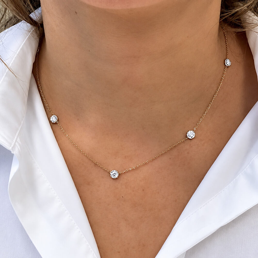 A delicate 18K yellow gold chain necklace with four small, clear round-cut diamonds spaced along the chain, shown worn on a model's neck over a white collared shirt.