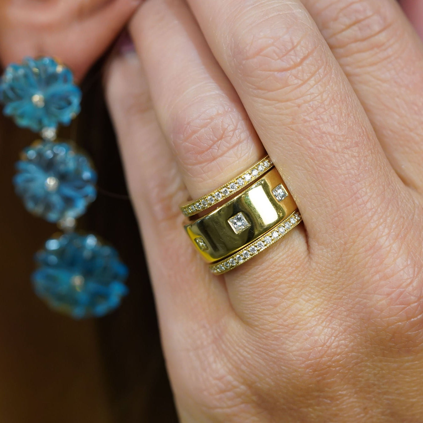 Close-up of a hand wearing 18K gold band ring with flush set diamonds