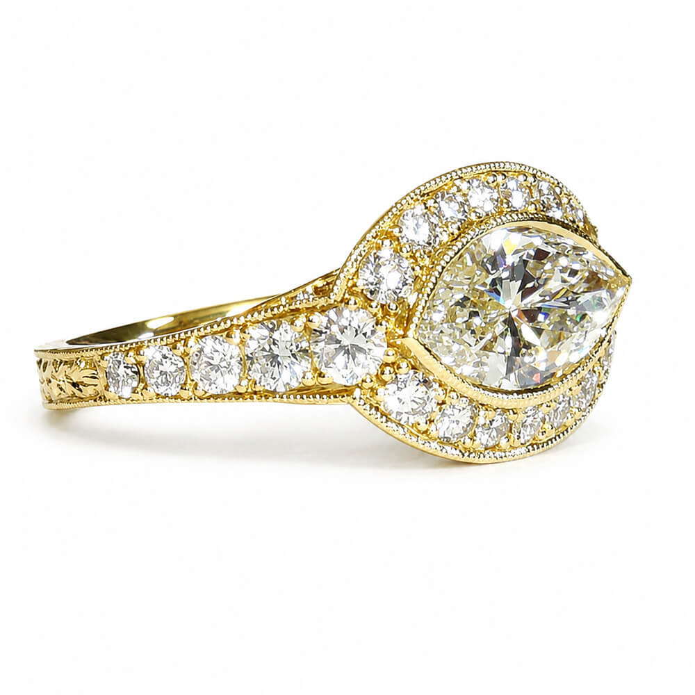An 18K yellow gold diamond ring with a large marquise-cut center stone and multiple round  diamonds along the band and halo, shown on a clean white background.