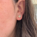 Close-up of an ear wearing a floral design earring with diamonds