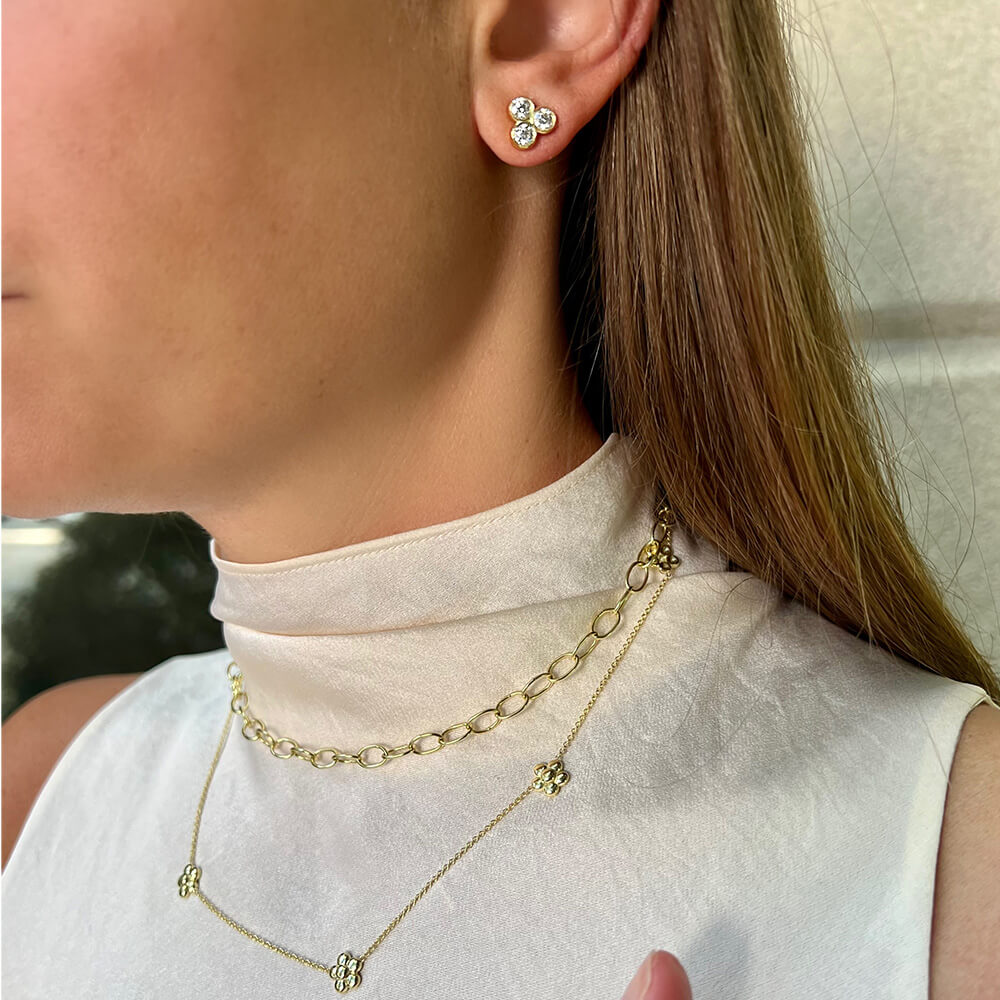 Close-up of a soman wearing gold chain necklaces and earrings.