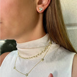 Close-up of a soman wearing gold chain necklaces and earrings.