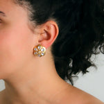 Close-up of a woman wearing a gold daisy-shaped earring with moonstones and diamonds