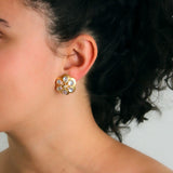 Close-up of a woman wearing a gold daisy-shaped earring with moonstones and diamonds