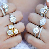 Close-up of hands wearing various diamond rings on a blurred background