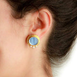 Close-up of an Elizabeth Locke 19K gold earring worn on a woman's ear with a plain background