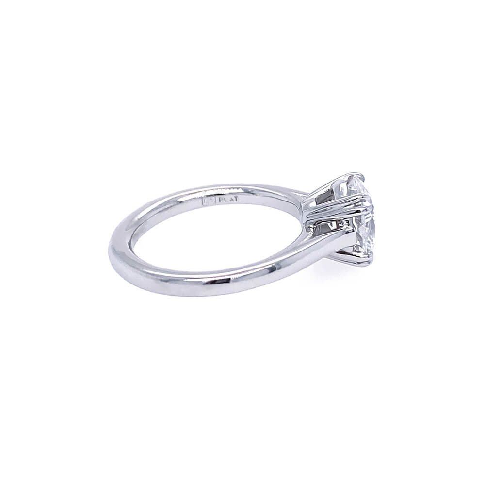 A platinum diamond ring with an oval brilliant-cut center diamond in a double fang four-prong setting, shown from a side profile view on a plain white background.