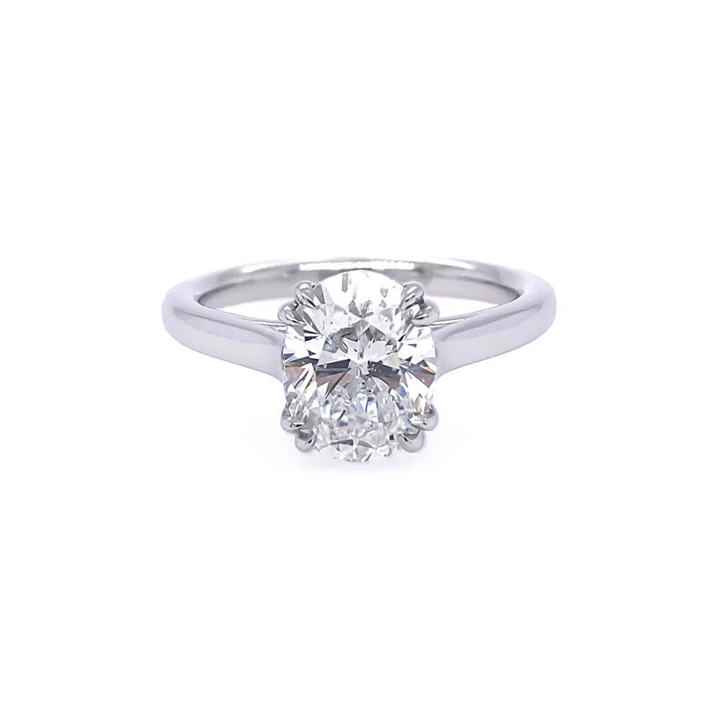 A classic solitaire engagement ring featuring an oval brilliant-cut diamond set in a polished platinum band, shown against a plain white background.