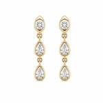 A pair of 14K gold dangle earrings with three bezel set diamonds in each earring, on a plain white background.