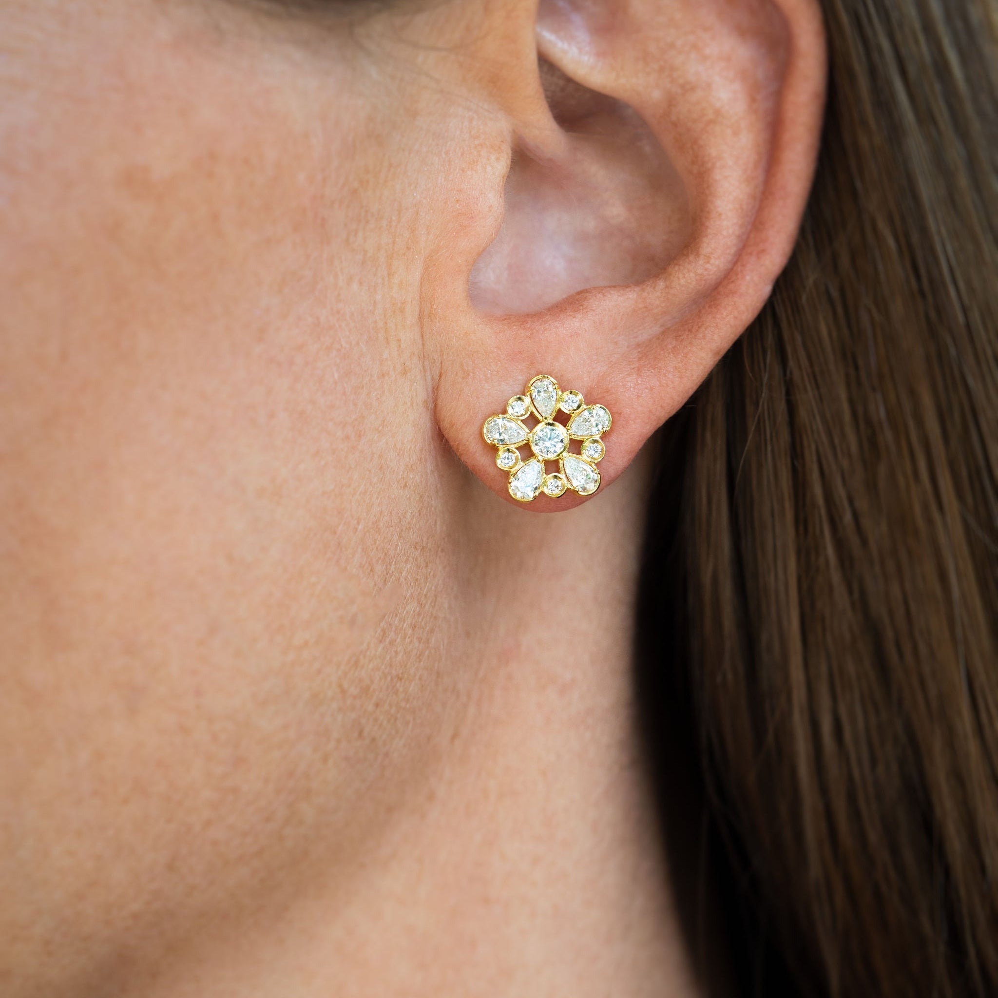 Close-up of a woman wearing 18k yellow gold diamond earrings designed by Laura Pearce.