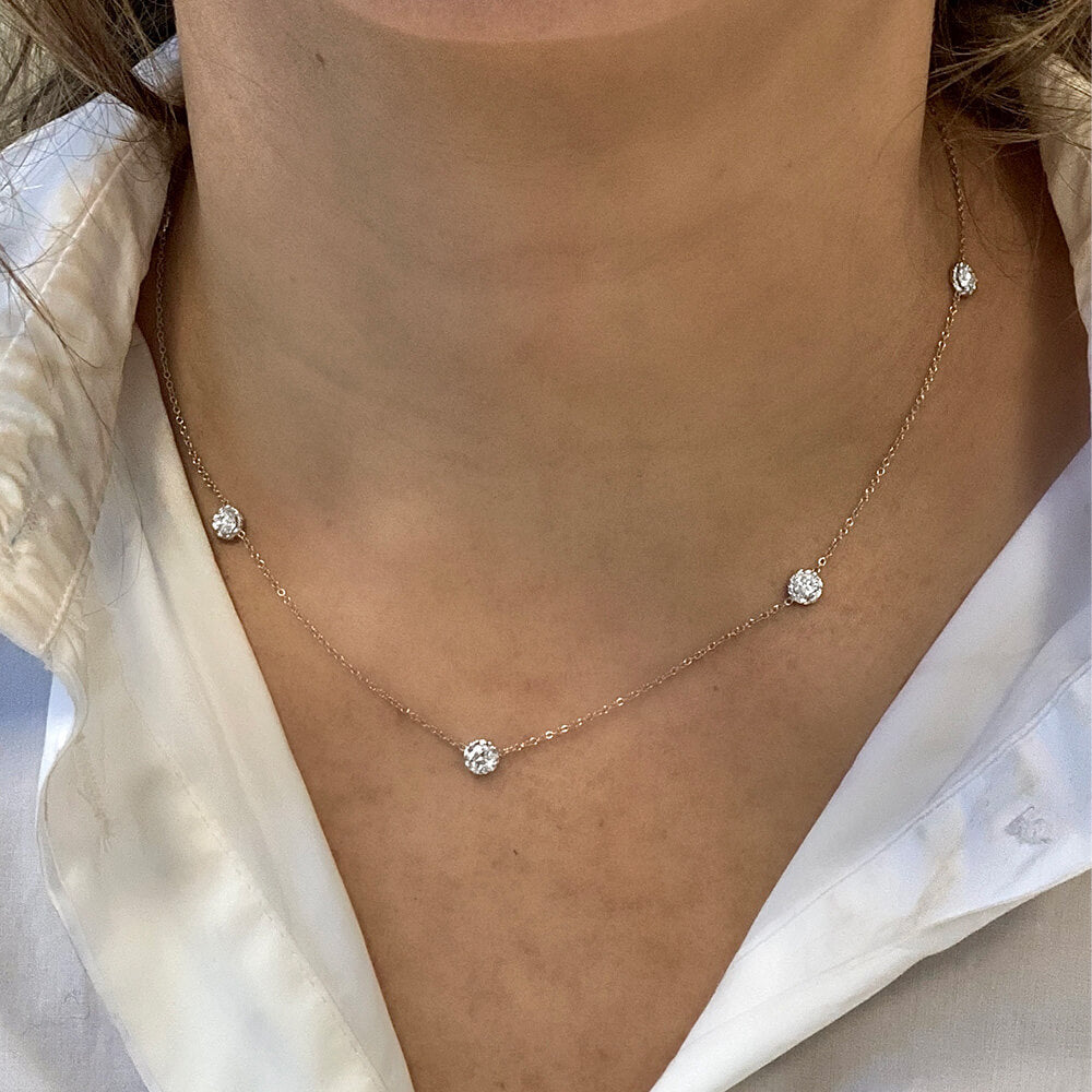 Necklace with small diamond-like pendants on a person wearing a white shirt.