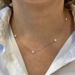 Necklace with small diamond-like pendants on a person wearing a white shirt.