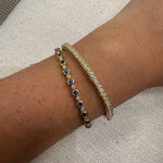 Close-up of a wrist wearing two bracelets on a textured beige background