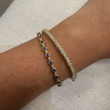 Close-up of a wrist wearing two bracelets on a textured beige background