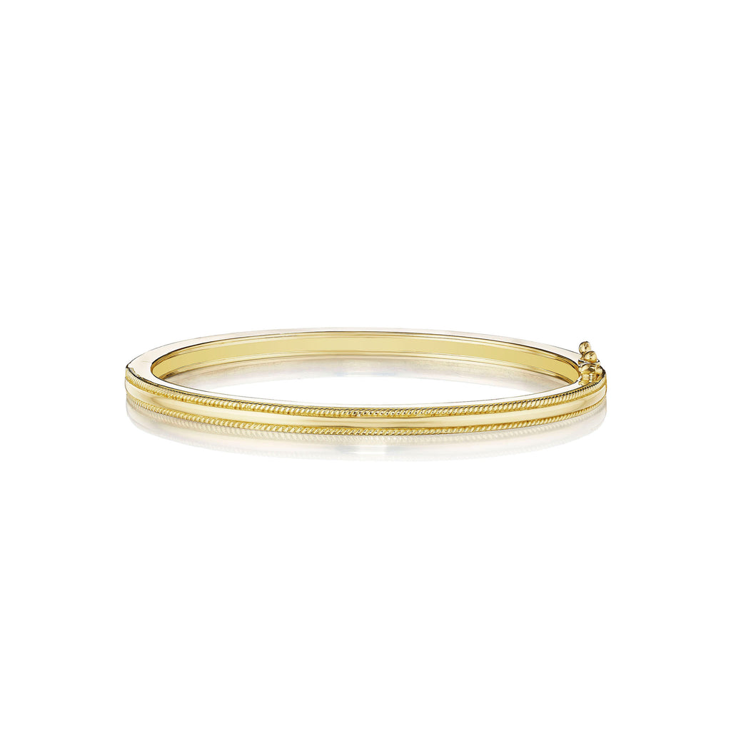 An 18K yellow gold thin bangle with a twist edge, designed by Penny Preville