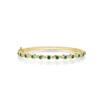A yellow gold bangle bracelet with green emerald stones and diamond accents.