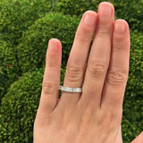 Hand wearing a platinum ring with 7 diamond stones totalling 1.65 carats against green blurred background