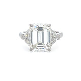 Diamond ring with emerald-cut center stone on a white background