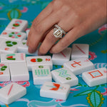 Woman's hand wearing Estate 5.4 carat Diamond ring playing with Mahjong tiles on a colorful board